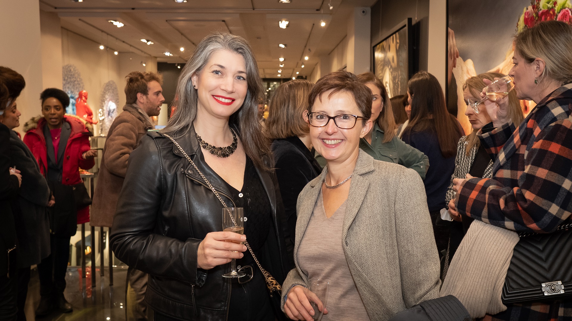 Visual aid: two women posing for a photographer at an event in a London art gallery